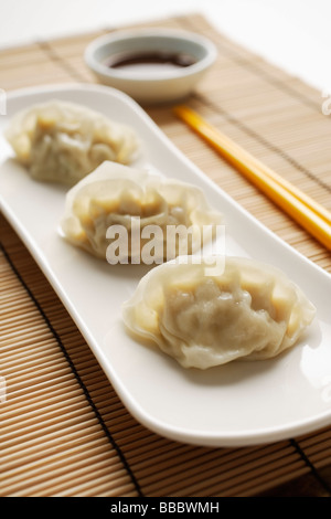 3 cotte al vapore gnocchi gyoza poste su piastra bianca con la salsa sul lato Foto Stock