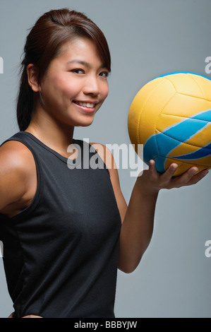 Giovane donna con la pallavolo sorridente in telecamera Foto Stock