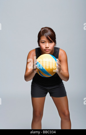 Giovane donna con la pallavolo sorridente in telecamera Foto Stock