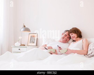 Eldery giovane mangiare a letto Foto Stock