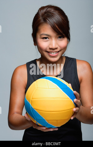 Giovane donna con la pallavolo sorridente in telecamera Foto Stock