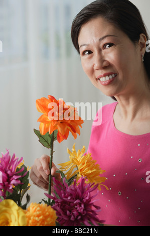 Donna matura azienda fiori, sorridente in telecamera, ritratto Foto Stock