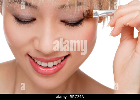 Una giovane donna si applica eye shadow Foto Stock