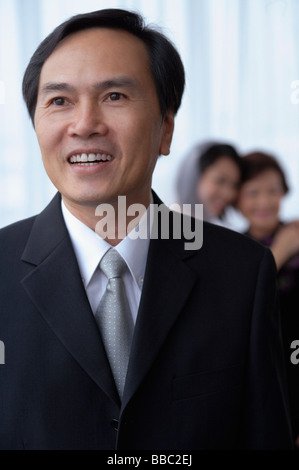 Un uomo sorride mentre una sposa e madre abbraccio in background Foto Stock