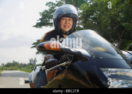 Donna matura in sella motocicletta e indossando il casco Foto Stock