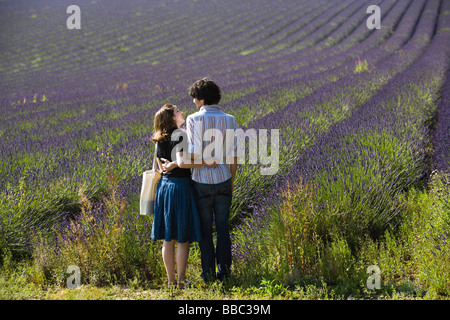 Una giovane coppia a piedi nei campi di lavanda in fiore a Snowshill lavanda, il Costwolds, Gloucestershire, Regno Unito Foto Stock