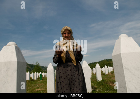 Una donna musulmana bosniaca prega tra tombe dei suoi parenti, vittime del genocidio Srebrenica, nel cimitero di Potocari, vicino a Srebrenica, in Bosnia Foto Stock