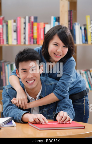 Matura in biblioteca, abbracciando la donna uomo da dietro Foto Stock