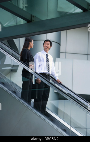 Imprenditore e imprenditrice su escalator Foto Stock