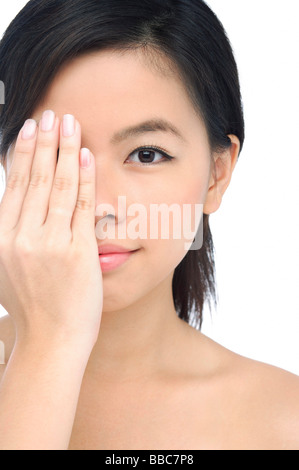 Giovane donna che copre la metà del suo viso con la sua mano Foto Stock