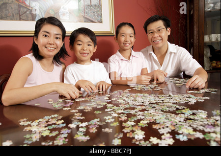 Famiglia di quattro persone in soggiorno lavorando su puzzle Foto Stock