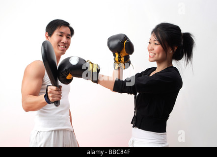 Giovane donna con i guantoni, praticando con trainer Foto Stock
