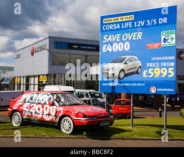 Un vecchio battere auto in un garage e il piazzale antistante la pubblicità il £2.000 scrapage governo regime. Foto Stock