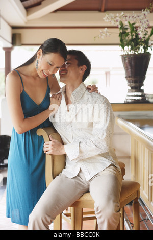 Giovane accanto al banco bar, uomo whispering in womans orecchio Foto Stock