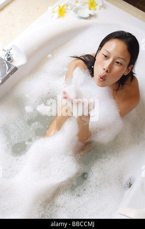 Donna con bolla bagno, soffiando schiuma di sapone Foto Stock