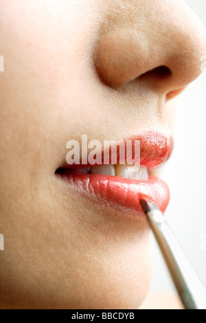 Close up della donna di bocca, mettendo il rossetto con labbro pennello Foto Stock