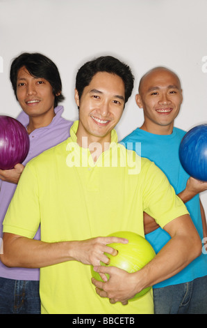 Tre uomini che tengono le palle da bowling, sorridente in telecamera Foto Stock