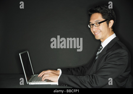 Imprenditore indossando occhiali, con laptop, sorridente in telecamera Foto Stock
