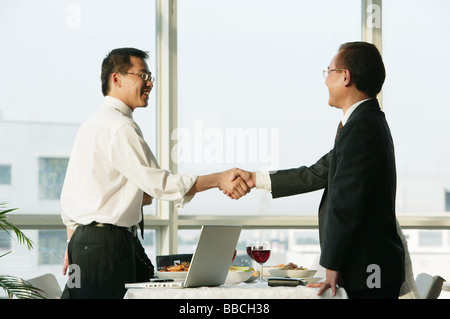 Imprenditori stringono le mani sulla tavola da pranzo Foto Stock