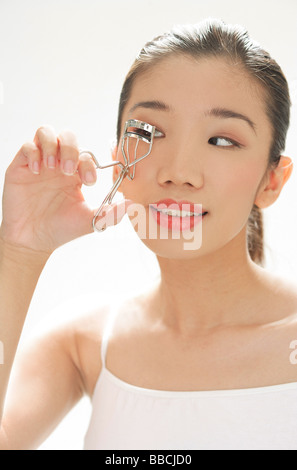 Donna che utilizza il bigodino di ciglia Foto Stock
