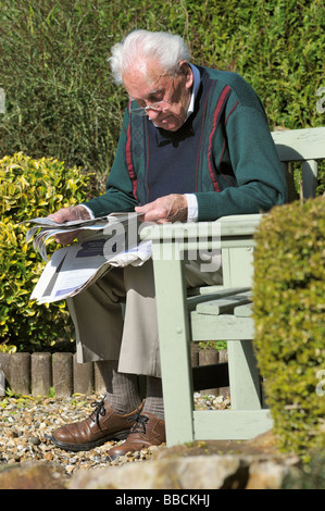 Anziano gentiluomo leggendo un giornale in giardino Foto Stock