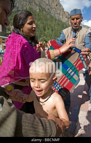Ragazzo avente la sua testa rasata lavato con acqua santa dal fiume Gange. Mundan cerimonia. Gangotri. Uttarakhand. India Foto Stock