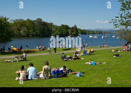 Persone relax sulle rive del lago di Windermere è sceso a piedi Park, Parco Nazionale del Distretto dei Laghi, Cumbria, England Regno Unito Foto Stock