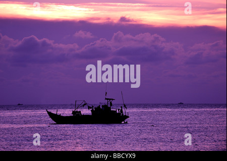 Barca da pesca stagliano contro il sole di setting. Appendere Dua Bay, Bai Truoc (Fronte Spiaggia o Tam Duong), Vung Tau, Vietnam Foto Stock