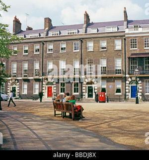 La gente seduta su una panchina di fronte a una fila di xviii C terrazzati case Georgiane alloggiamento in Bedford Square Bloomsbury Londra Inghilterra KATHY DEWITT Foto Stock