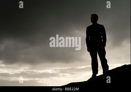 Silhouette di un uomo in piedi sulla skyline contro un burrascoso moody broody dark sky Foto Stock