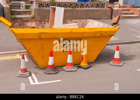 I costruttori di un cassonetto in strada con il traffico coni posto attorno ad esso per avvertire di un hazzard nel Regno Unito Foto Stock