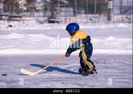 Little Boy giocare ad hockey su un laghetto congelato, Fuschlsee, Salzburger Land, Austria Foto Stock