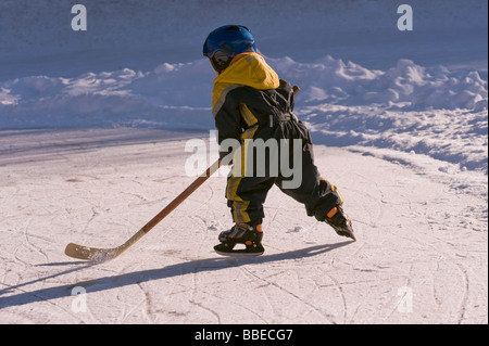 Little Boy giocare ad hockey su un laghetto congelato, Fuschlsee, Salzburger Land, Austria Foto Stock