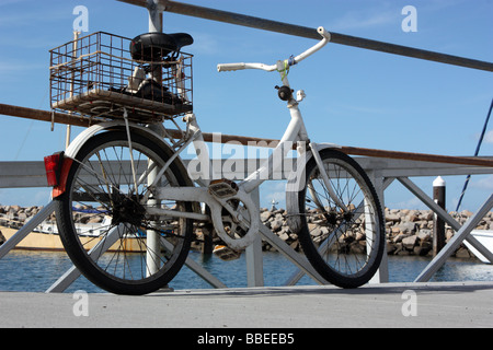 Vecchio PUSHBIKE parcheggiato su un molo cielo blu di sfondo BDA ORIZZONTALE Foto Stock