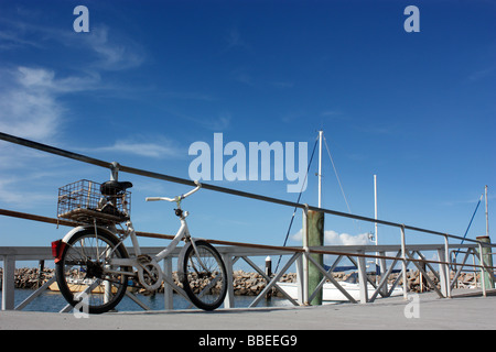 Vecchio PUSHBIKE parcheggiato su un molo cielo blu di sfondo BDA ORIZZONTALE Foto Stock