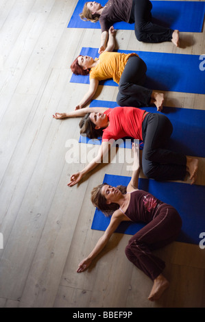 Le donne nella classe di yoga facendo torsione spinale Foto Stock