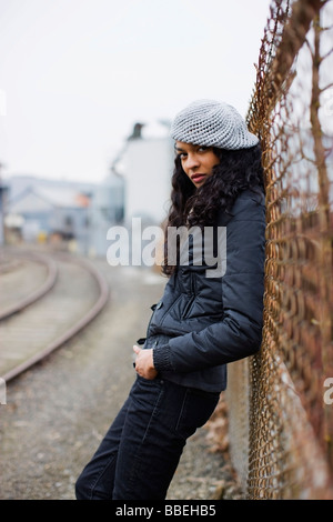 Donna appoggiata contro una recinzione in Urban Area Industriale di Portland, Oregon, Stati Uniti d'America Foto Stock