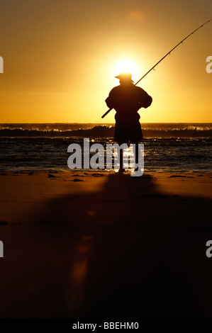 Pescatore sulla spiaggia al tramonto Foto Stock