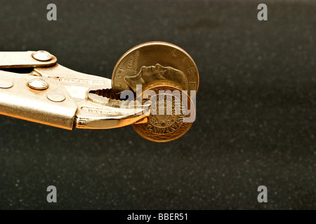 Metallo vise grip tenendo un American Silver Dollar coin e Inghilterra è un due libbre di rame e di argento moneta Foto Stock