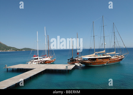 Barche a vela in prossimità della banchina in legno presso la costa di Bodrum Foto Stock