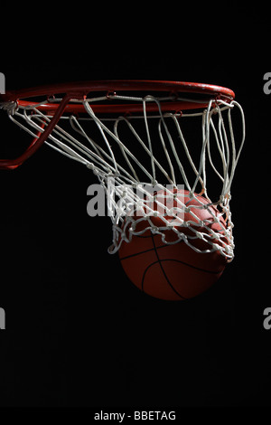 La pallacanestro attraversando hoop Foto Stock