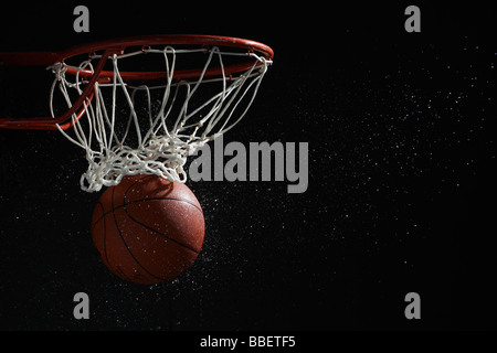 La pallacanestro attraversando hoop Foto Stock