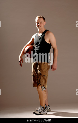 Giovane con una gamba protesico tenendo un basket Foto Stock