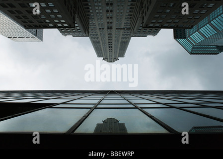 La riflessione del grattacielo di vetro sulla facciata di edificio sul lato opposto della strada, visto dal di sotto Foto Stock
