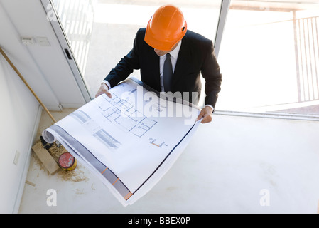 Uomo in tuta indossare elmetto guardando il blueprint Foto Stock