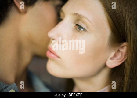 Giovane donna che guarda lontano lontanamente come uomo bacio sulla guancia Foto Stock