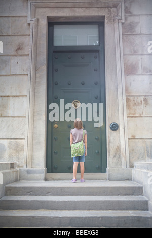 La ragazza di fronte a una grande porta Foto Stock