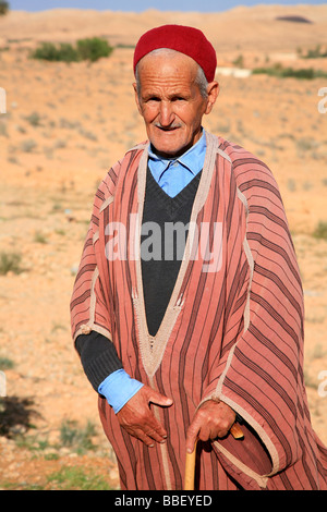 Il vecchio uomo con i baffi indossando un tradizionale djellaba e red fez in Tataouine, Tunisia Foto Stock