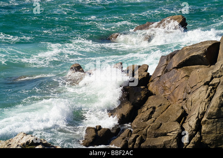 Il mare e le onde contro le rocce sulla riva Foto Stock