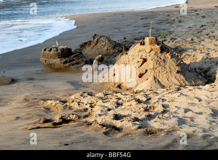 Un bambino il castello di sabbia in procinto di essere lavati via dalla marea. Oregon USA Foto Stock